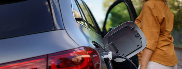 Woman waiting while electric car charging, close-up. stock photo