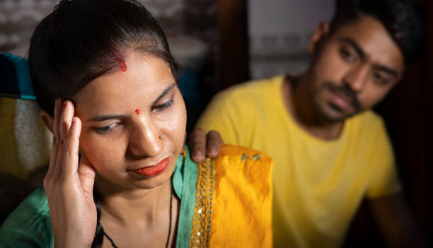 istock Indian man consoling his wife who is thinking about problems by holding her head at home. 1431917075