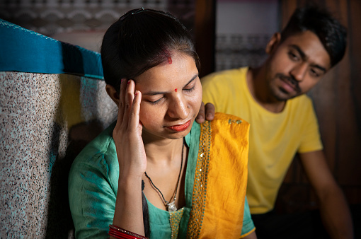 Hombre indio consolando a su esposa que está pensando en los problemas sosteniendo su cabeza en casa. photo
