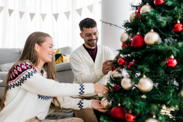 istock Happy young couple wearing sweaters having fun decorating various baubles on the Christmas tree in the living room at home. Enjoying and celebrating the Christmas holiday. 1431917865