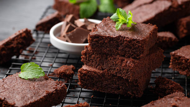 schokoladen-brownies garniert mit minze auf kühlgestell. süßes essen - brownie baked bakery brown stock-fotos und bilder