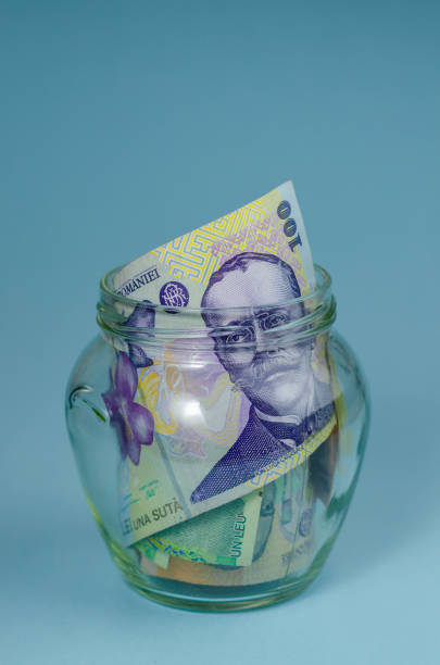 istock Glass Jar Full Of Romanian RON Bank Notes On A Blue Background 1431918588