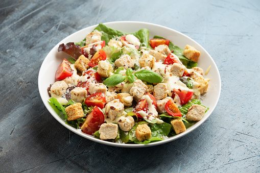 Vegetarian ceasar salad with meat free chicken pieces cherry tomatoes croutons and lettuce in white plate