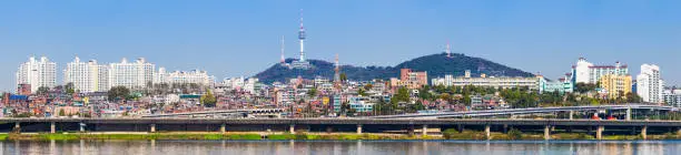 Panoramic view across the Han River beside the Banpo Bridge to the crowded highrise cityscape of central Seoul, overlooked by the iconic spire of Namsan Tower, Korea.
