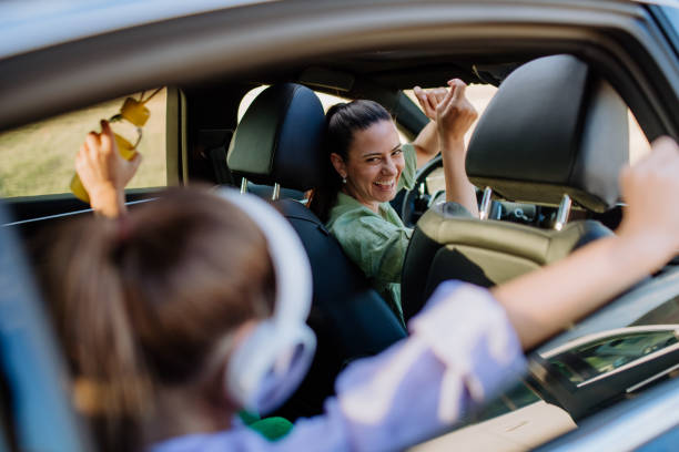 Young mother and her daughter having fun in their electric car. stock photo