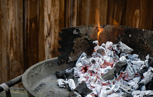 Hardwood charcoal burns on the grill. Wood texture, flame, sparks.