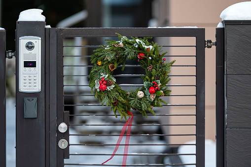 Christmas wreath on a metal gate at the entrance of a residential building, close-up