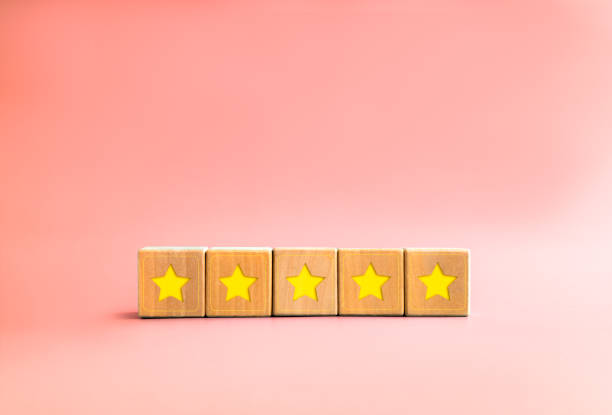 istock Client feedback survey with yellow star on five wooden cube blocks on pastel pink background with copy space, minimal style. Five stars customer product rating review. Client experience satisfaction. 1431927918