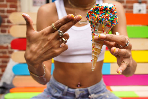 Hand holding vanilla icecream cone on yellow background