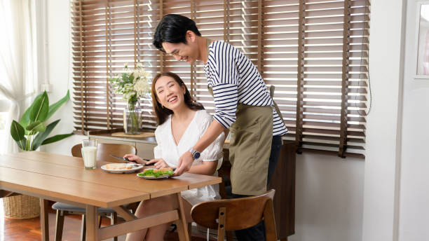 Young smiling asian couple having breakfast  on the table in the morning , family concept. stock photo