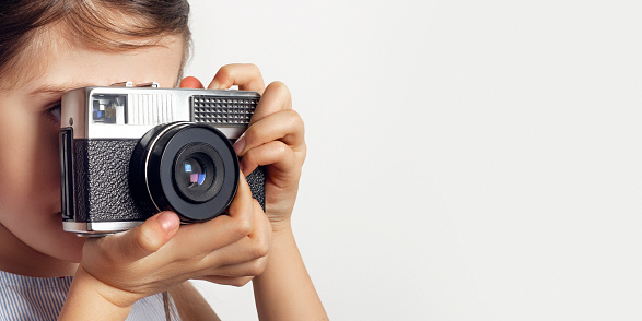 A cute girl taking photographs with a vintage 35mm film camera. Photography banner concept
