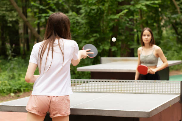 table tennis outdoor, teenager playing ping pong with table tennis rackets in the summer in the park, active leisure stock photo