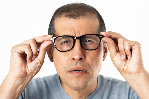 adult with glasses straining his eyes because he can't see, isolated with white background
