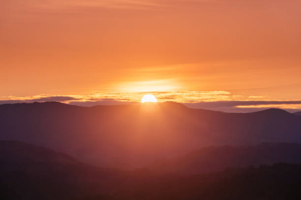 красивый восход солнца. солнечные лучи освещают луг деревьями. весеннее утро. пейзаж с высокими горами. панорамный вид. природные пейзажи. ф - twilight стоковые фото и изображения