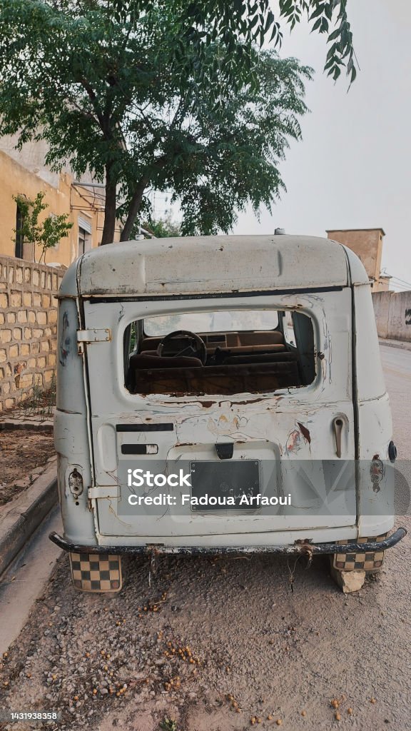 An Old Abandoned Rusty Car An Old abandoned car covered in rust, with no windows, parked on the sidewalk of a small Tunisian village. Abandoned Stock Photo