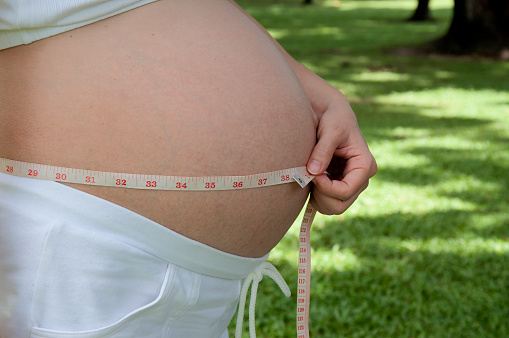 pregnant woman with waist tape take photo at Lumpini Park, Rama IV, Bangkok, Thailand.