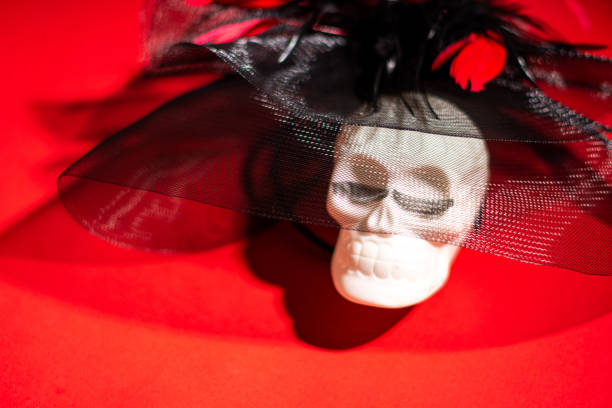 Cheerful Human skull with eyelashes on a red background. Halloween decorations. Halloween concept. Flat lay, top view, copy space.