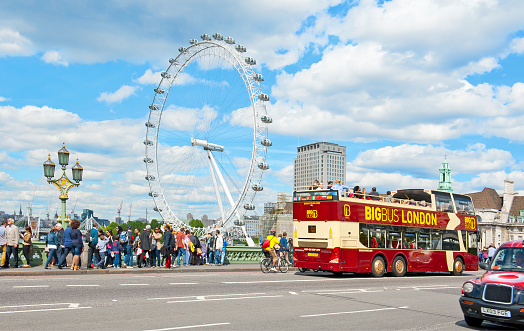 London, England - May 30, 2015:  London Eye and open top double decker bus in the city center in London