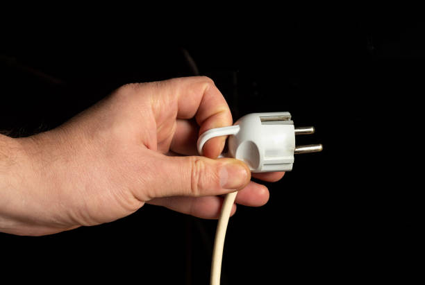 istock Man hand plug in power plug close up on black background 1431951974