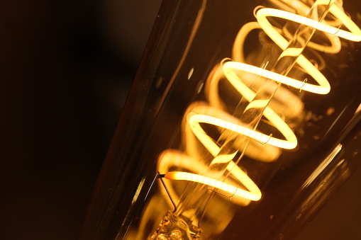macro of yellow spiral light bulb filament at night.