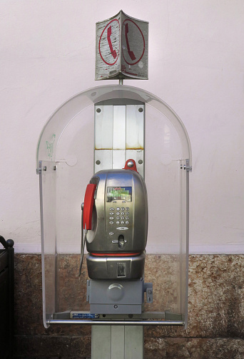 an old public pay telephone, in a little kiosk, on the street in downtown Lecco, Italy, Lombardy