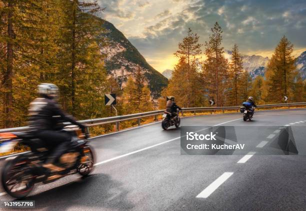 Travel Concept Group Of People Travelers On Motorcycles Ride On An Asphalt Road In The Mountains At Sunset In The Italian Alps Beautiful Autumn Landscape Stock Photo - Download Image Now
