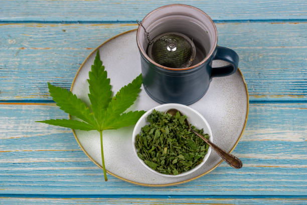 cannabis tea with cup and tea strainer - cannabis, marijuana - photography sign table ganja imagens e fotografias de stock