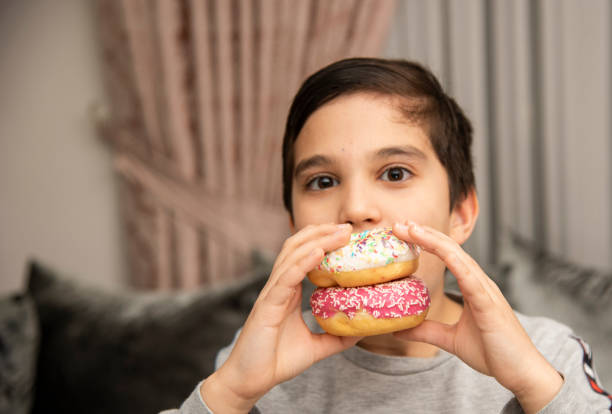 istock Cute little boy holding donuts 1431967203