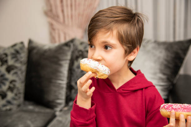 istock Cute little boy holding donuts 1431967410