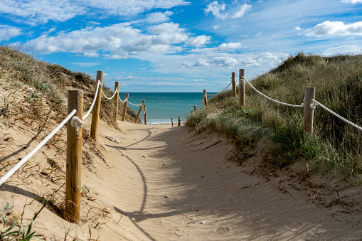 View of a sandy beach and sea from the top of a grass covered dune. extended depth of field