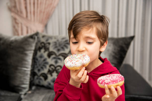 istock Cute little boy holding donuts 1431967787
