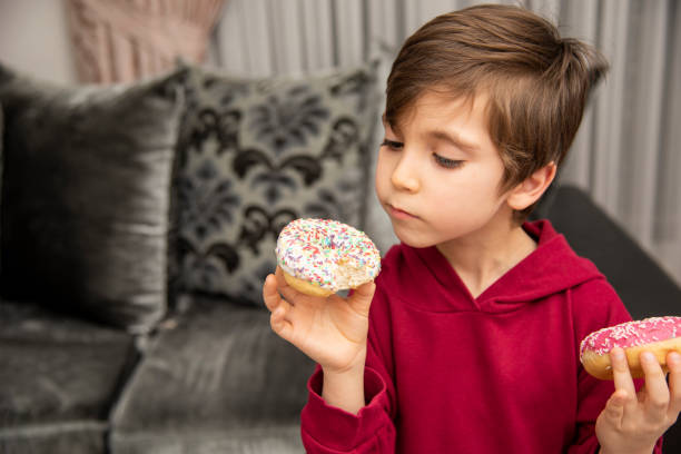 istock Cute little boy holding donuts 1431967804