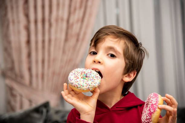 istock Cute little boy holding donuts 1431968688