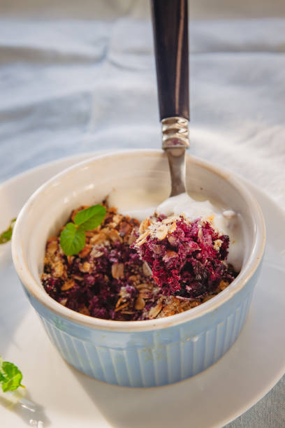 baked oat-blueberry crumble with mint in a white and blue plate on a rustic linen tablecloth. Save the space, top view. The concept of healthy proper nutrition for breakfast, vegetarianism