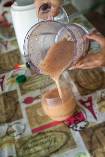 whip a smoothie in a blender and pour it into a glass.