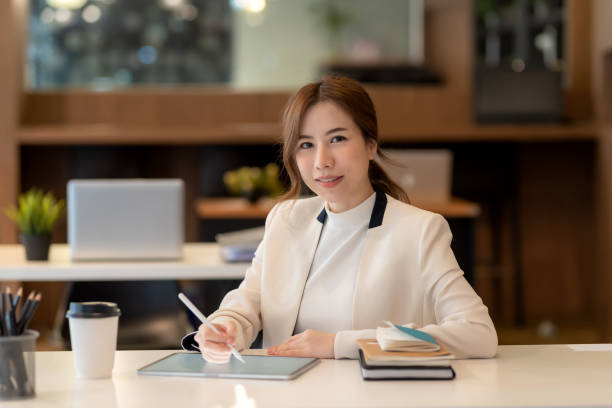 istock Young Asian business woman sitting think about work using a tablet at the office. 1431974691