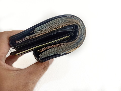 a man hold wallet filled with much money so thick, can't be folded, an illustration photo of having a lot of money after payday isolated on white