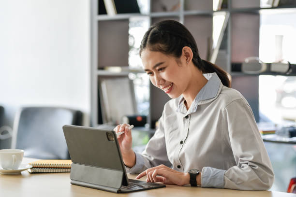 istock Young Asian business woman sitting think about work using a tablet at the office. 1431974843