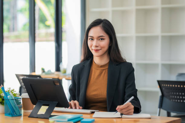 istock Young Asian business woman sitting think about work using a tablet at the office. 1431975565