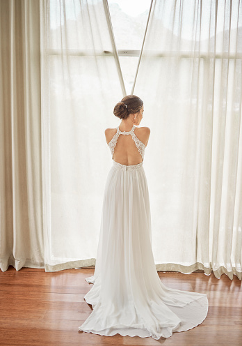 Bride by a window in a wedding dress with luxury fashion or designer fabric. Back or behind of an woman with bridal beauty design for marriage, wealth or creative style and curtain for elegance