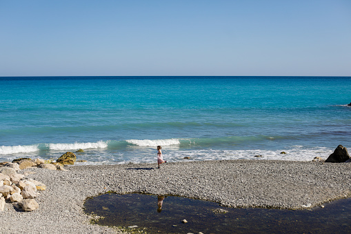 Little girl running on the beach on the French riviera during a sunny spring day.