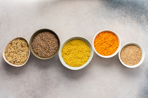 Various grain cereals in bowls on a light background, top view