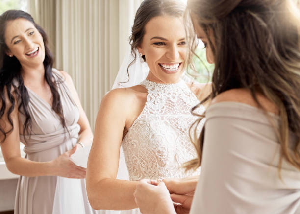 mariage, mariée et amis d’une femme excitée et heureuse pour une occasion joyeuse de mariage. sourire féminin en amitié avec des demoiselles d’honneur ensemble dans une pièce pour aider à préparer la cérémonie - wedding dress wedding domestic room bride photos et images de collection