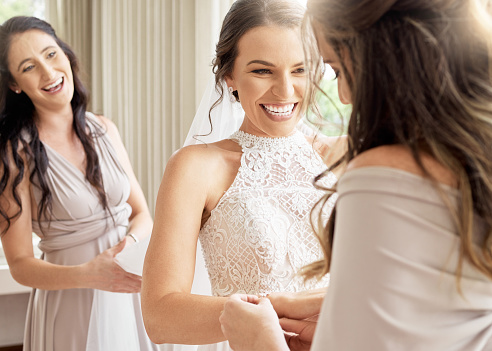 Wedding, bride and friends of a woman excited and happy for joyful occasion of marriage. Female smile in friendship with bridesmaids together in a room to help prepare for ceremony