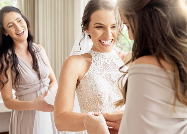 Wedding, bride and friends of a woman excited and happy for joyful occasion of marriage. Female smile in friendship with bridesmaids together in a room to help prepare for ceremony stock photo