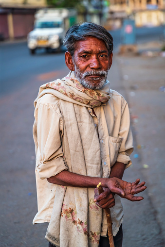 Poor Indian man standing on a street and asking for support.