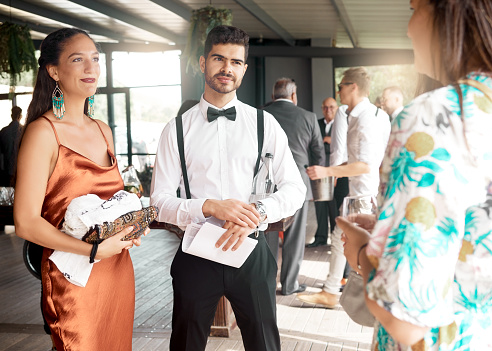 Event, wedding or gala with audience, guest or people in fashionable, fancy and stylish clothes enjoying conversations, listening and speaking. A group, people and guests talking at luxury party.