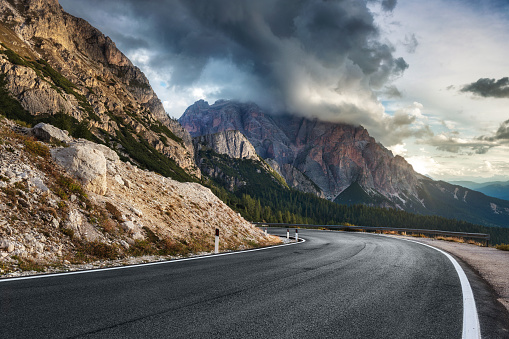 Highway in mountains in summer evening in Italy. Beautiful landscape with roadway. Empty asphalt road against the backdrop of a beautiful rock. Dolomites, Alps