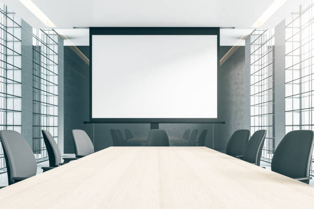 istock Front view on blank white screen with copyspace for your text or logo in modern boardroom with wooden table, grey chairs and walls and metal muntins on windows. 3D rendering, mockup 1431981882