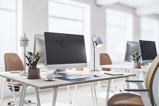 istock Perspective view on stylish work place in spacious sunny office with modern laptop, lamp, flowerpot and notes on light wooden table, brown and white chair on big window background. 3D rendering 1431981886